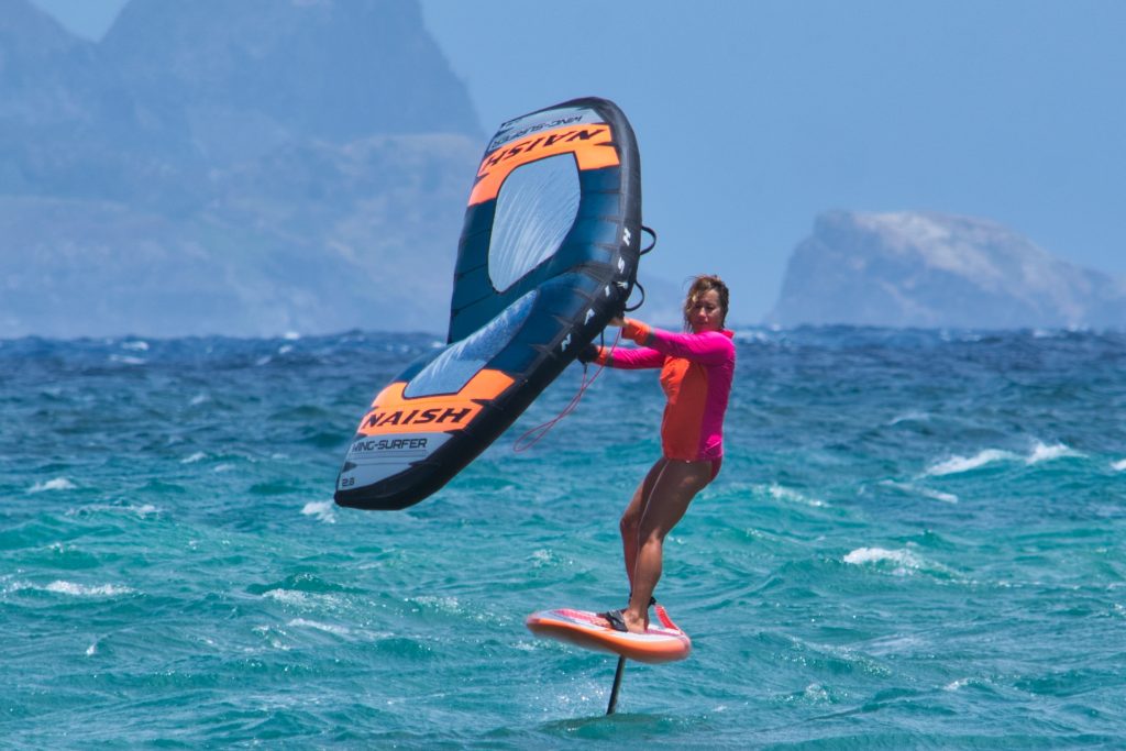 A wing foiler sailing on a foiling board